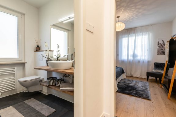 Modernes Badezimmer mit Holzwaschtisch und weißem Waschbecken und Schlafzimmer