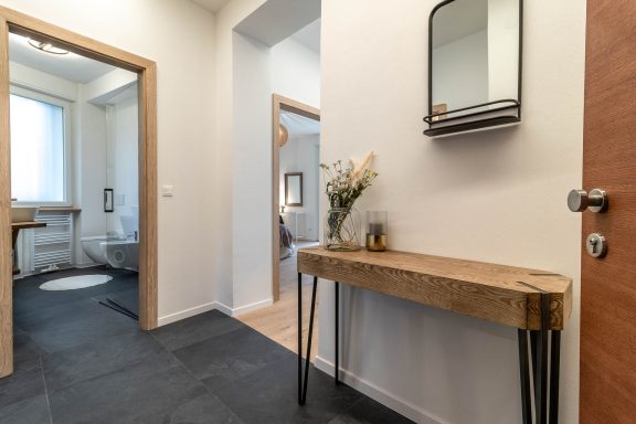 Sanierter Eingangsbereich mit Holzkonsole, Spiegel und modernen Details in Südtirol